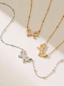 Detailed macro view of bow pendants with sparkling zircon pavé on beaded chains