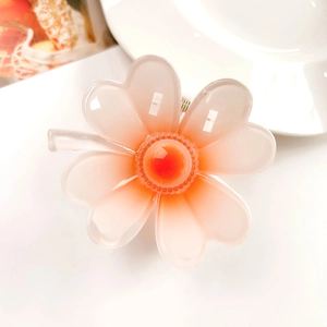 Macro detail of peach orange translucent resin flower hair claw with glossy jelly finish