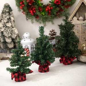 Three mini green Christmas trees with red plaid burlap bases for holiday tabletop decor