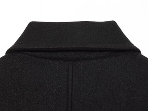 Detail of wool blend fabric texture and stitching on a black double-breasted short coat
