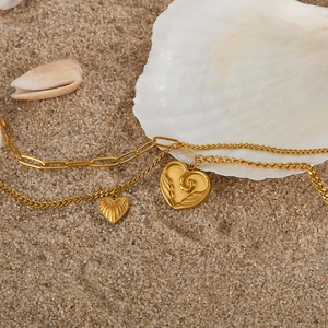 Close-up of golden double-layer heart necklaces on beach sand with white shells