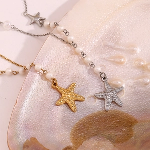 Detail of gold and silver starfish pendants with pearls on an iridescent shell