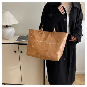 Brown vintage pleated tote bag with white TOTE BAG text shown in lifestyle interior setting