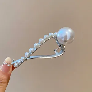 Minimalist silver metal hair claw clip with elegant white pearls on warm background