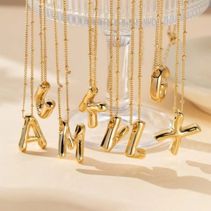 Detailed view of multiple golden puffy bubble letter pendants on polished chain links
