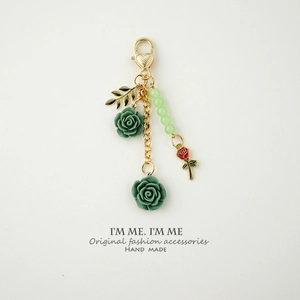 Detail of handmade resin rose keychain with green flowers and golden heart clasp