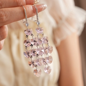 Macro view of silver tassel earrings featuring pink crystal hearts and zircon accents
