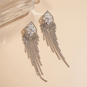 Macro detail of silver tassel earrings with geometric flower pattern and sparkling zircons