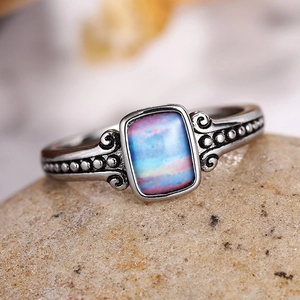 Vintage bohemian silver ring with drop-shaped blue-pink gradient stone on natural rock