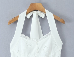 Détails d'un haut licou blanc avec broderie anglaise et boutons décoratifs à l'avant