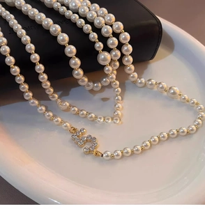 Detail of long pearl necklace with zircon-encrusted clasp and golden accents for women