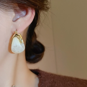 Close-up of retro U-shaped resin earrings with marble pattern on a female model