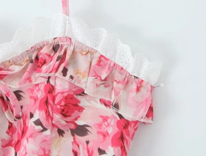 Close-up of pink rose floral fabric with detailed white lace embroidery trim on the edge