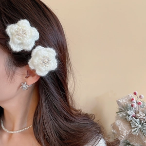 Gros plan sur la barrette fleur en tricot blanc avec perle sur le profil du modèle