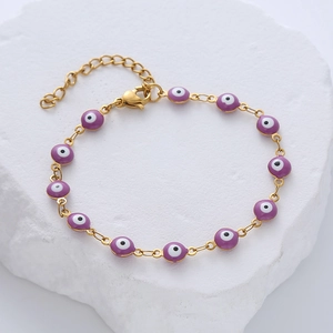Detail of gold evil eye bracelet with purple charms on white stone base and lobster clasp