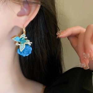 Détail de boucles d'oreilles papillon en cristal bleu portées montrant l'élégance chic
