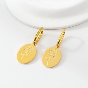 Detailed macro view of golden oval earrings featuring delicate rose flower etching