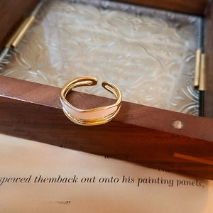 Detail shot of a double-layered gold ring showing the 925 silver stamp and cream enamel