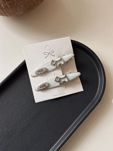 Close-up of silver-gray puppy hair clips with 'egg' lettering on a display card