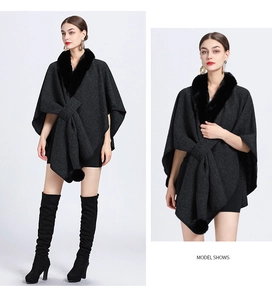 Detail of dark grey knit poncho featuring black faux fur collar and decorative tassel balls