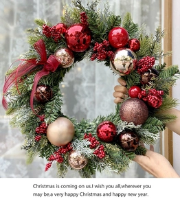 Close-up of a festive Christmas wreath with pine needles, red berries and ornaments