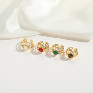 Detail of adjustable gold rings with mother of pearl, malachite and onyx on white silk