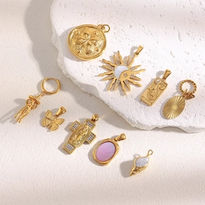 Detailed view of 18K gold plated charms including cross, sun, and butterfly designs