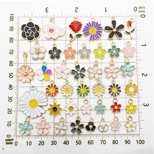 Assorted DIY flower pendants in alloy with enamel and pearls on a measurement board