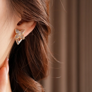 Close-up of model wearing clover stud earrings with gold plating and zircon crystals