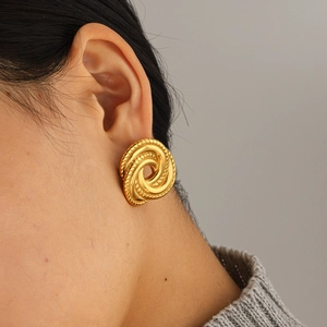 Boucles d'oreilles torsadées dorées en acier inoxydable portées par un modèle
