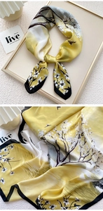 Detailed view of floral bird print silk scarf with lustrous satin texture and drape