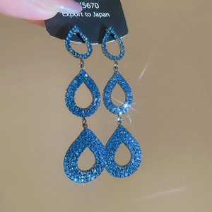 Macro shot of long blue tassel earrings with sparkling teardrop crystal pendants
