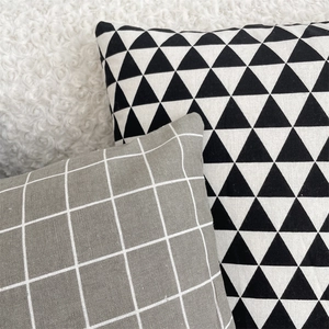 Detail of linen cushion covers showing geometric triangle and grey plaid patterns