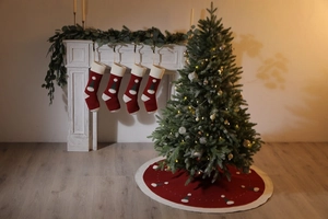 Détail de chaussettes de Noël rouges et jupe de sapin assortie près d'une cheminée