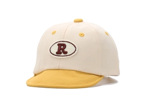 Vue détaillée de l'écusson brodé de la lettre R marron sur cette casquette pour bébé.