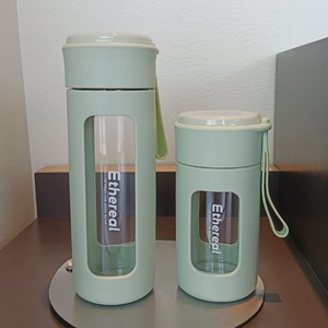 Close-up of green silicone-sleeved glass bottles with portable carry ropes and quotes