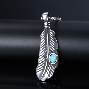 Detailed close-up of retro silver feather pendant with oval blue turquoise stone