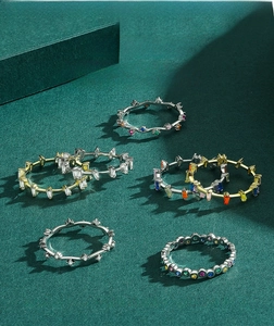 Close-up of rainbow stackable S925 silver rings with colorful gemstone inlays on green texture