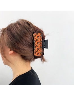Detail of Gothic Halloween hair claw featuring orange pumpkin Trick or Treat pattern