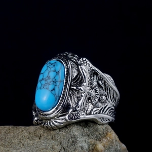 Detailed relief of an eagle and feathers on a vintage silver ring with turquoise stone