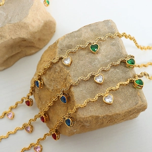 Gold chain necklace featuring colorful heart-shaped zircon pendants on textured stones