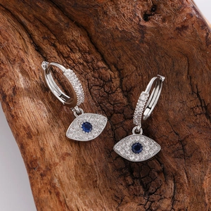 Macro detail of silver Evil Eye hoop earrings with blue stones and white zircons