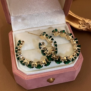 Detailed view of emerald green crystal hoop earrings inside a pink velvet jewelry box