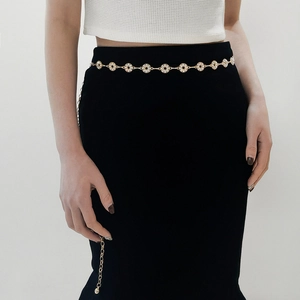 Detailed close-up of golden metal waist chain with sparkling rhinestones on a model