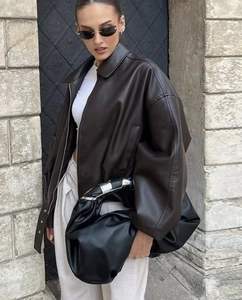 Outdoor street style shot of a dark brown vintage leather jacket with large black tote bag