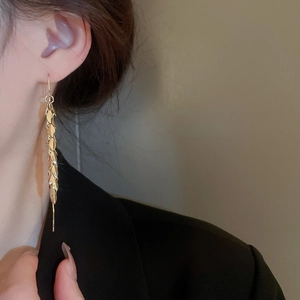 Close-up of elegant gold plated wheat leaf tassel earrings worn by a model in profile