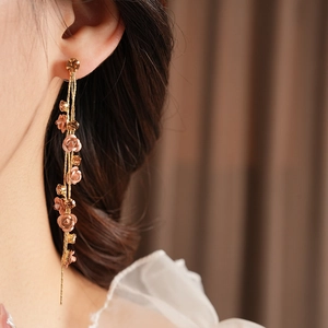 Macro shot of long tassel earrings with rose petals and sparkling rhinestones on model