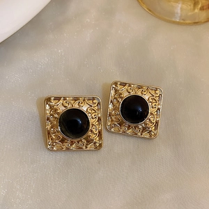 Detail of vintage square gold earrings with black gemstone and intricate filigree edge