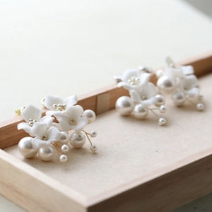 Detailed view of handmade ceramic flower and pearl bridal hair pins in gold finish