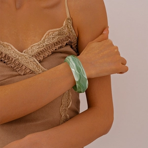 Close-up of a wide green marble acrylic cuff bracelet on a model wrist for fashion